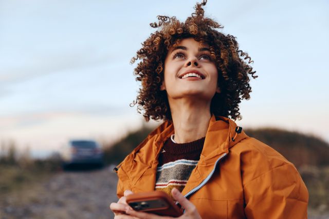 Een foto van een vrouw die buiten staat en naar de lucht kijkt