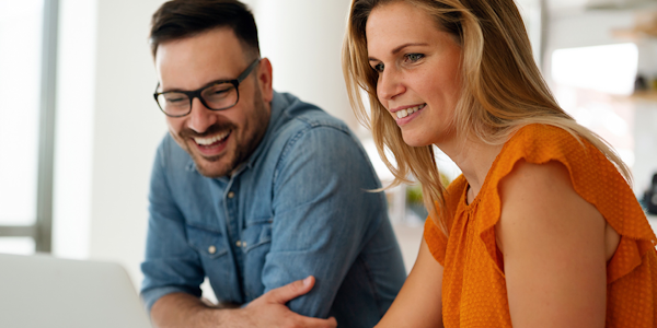 man en vrouw in oranje shirt achter laptop